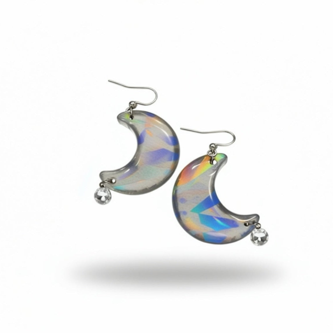 A pair of crescent moon-shaped dangle earrings made from iridescent opal-like resin with silver hooks and small clear crystal drops, shown against a plain white background.